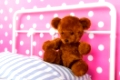 Girls bedroom with pink wall paper and stuffed bear